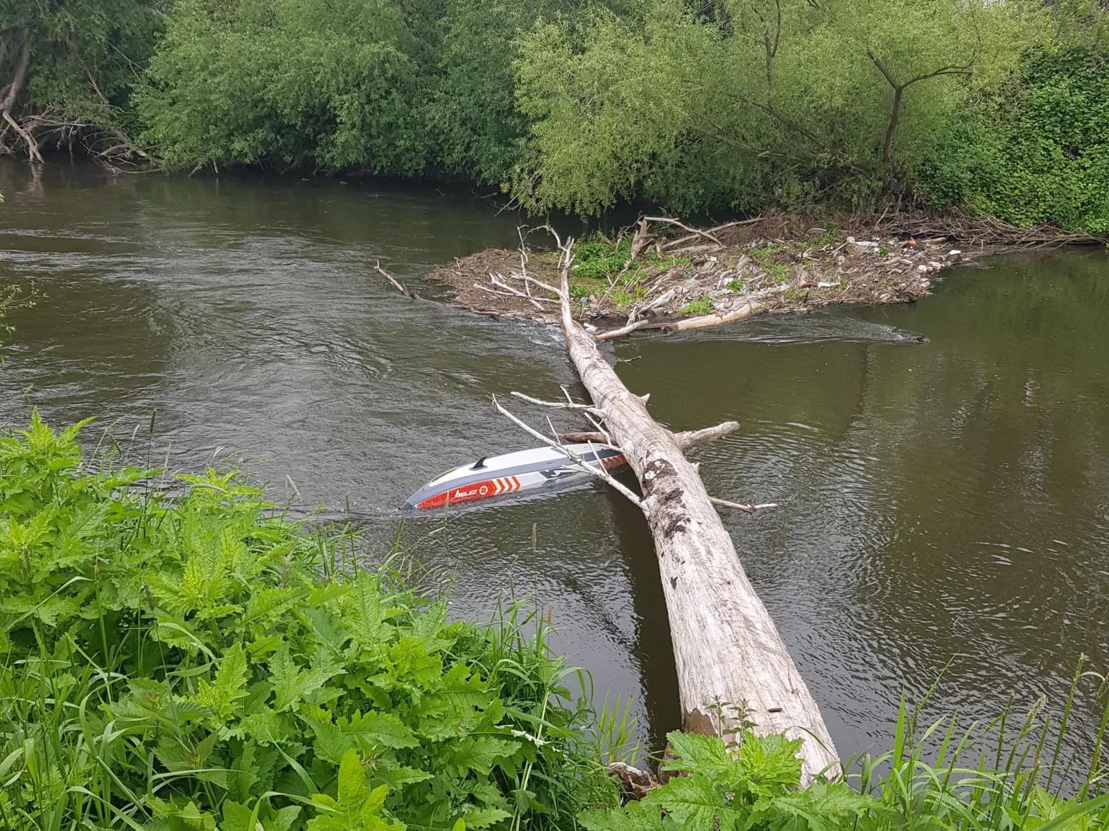 Ein Boot liegt unter einem Baumstamm im Wasser.